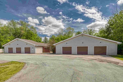 A large building with a grey roof and four garage doors.