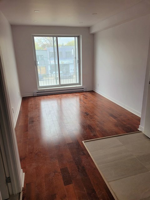 an empty living room with wood floors and a window