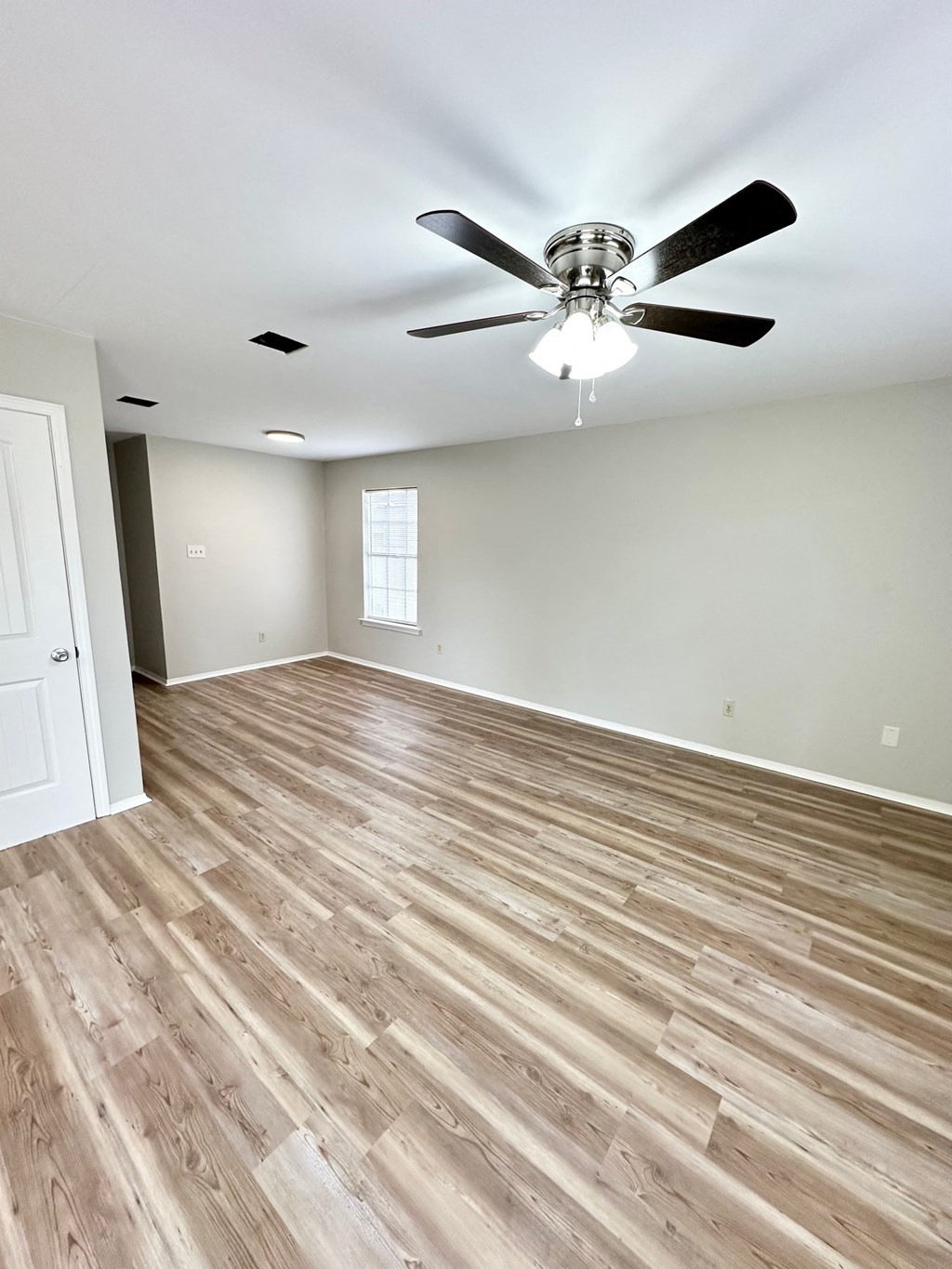 an empty living room with wood flooring and a ceiling fan