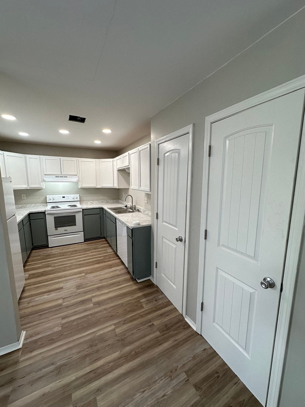 a small kitchen with white cabinets and a wooden floor