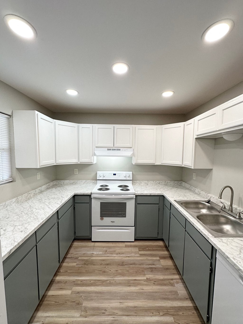 an empty kitchen with white cabinets and white counter tops and a stainless steel sink