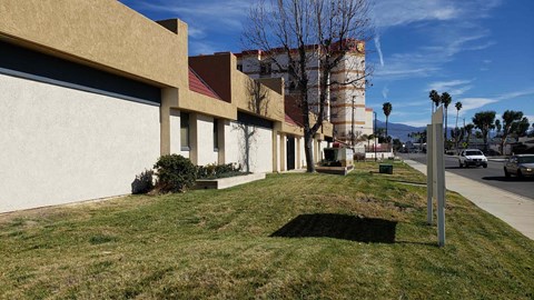 A building with a red roof and a white wall with a shadow of a tree on the ground.