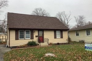 A small house with a red door and a sign in front.