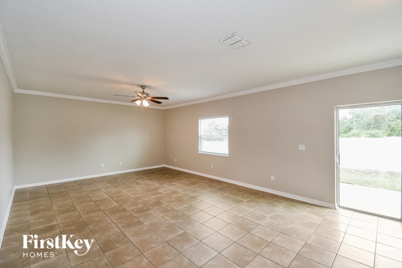 an empty living room with a ceiling fan and tiled floors