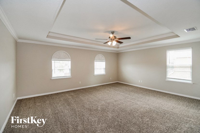 an empty room with a ceiling fan and three windows