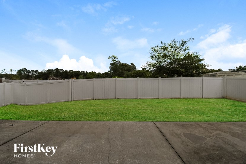 the backyard of a house with a white fence and grass