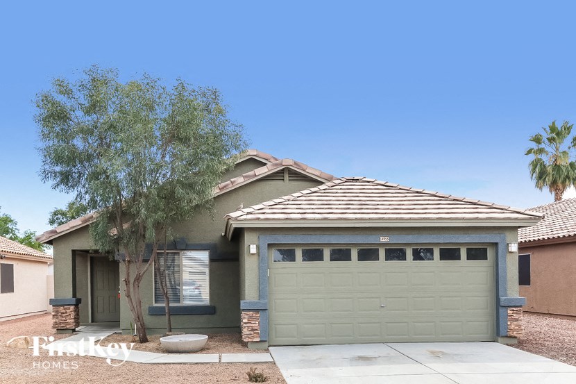 A house with a garage and a tree in front.
