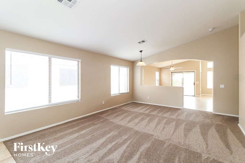 A spacious room with a carpeted floor and a large window.