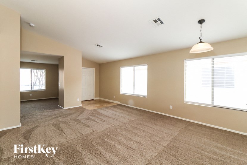 A spacious room with a carpeted floor and a hanging light fixture.