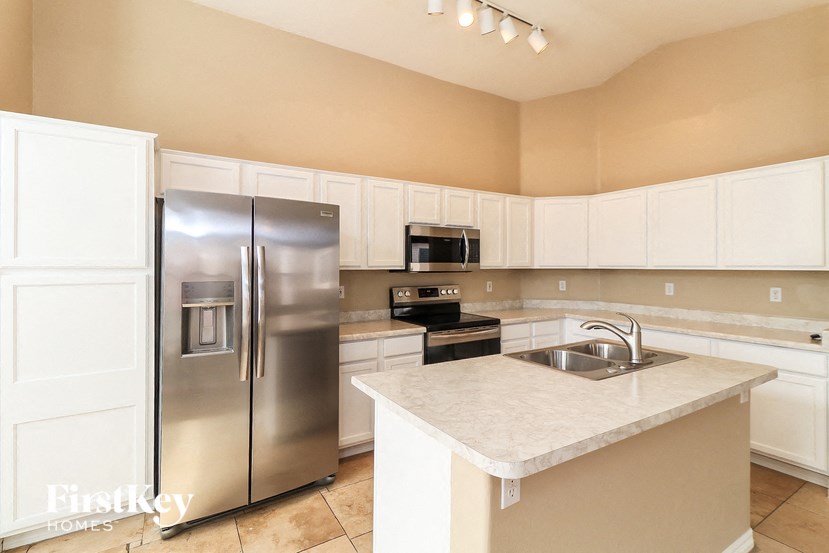A kitchen with a stainless steel refrigerator and white cabinets.