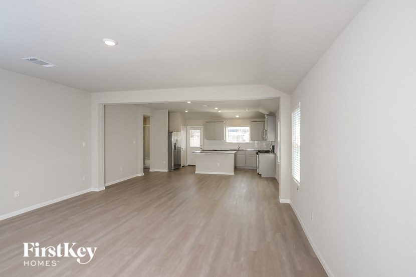 an empty living room and kitchen with wood flooring