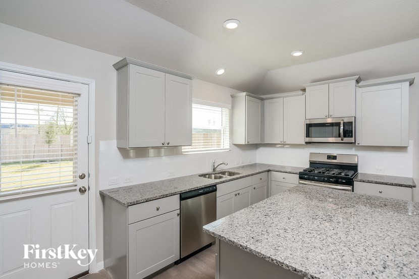 a white kitchen with granite counter tops and white cabinets