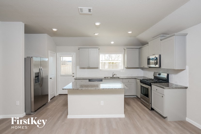 an empty kitchen with white cabinets and stainless steel appliances