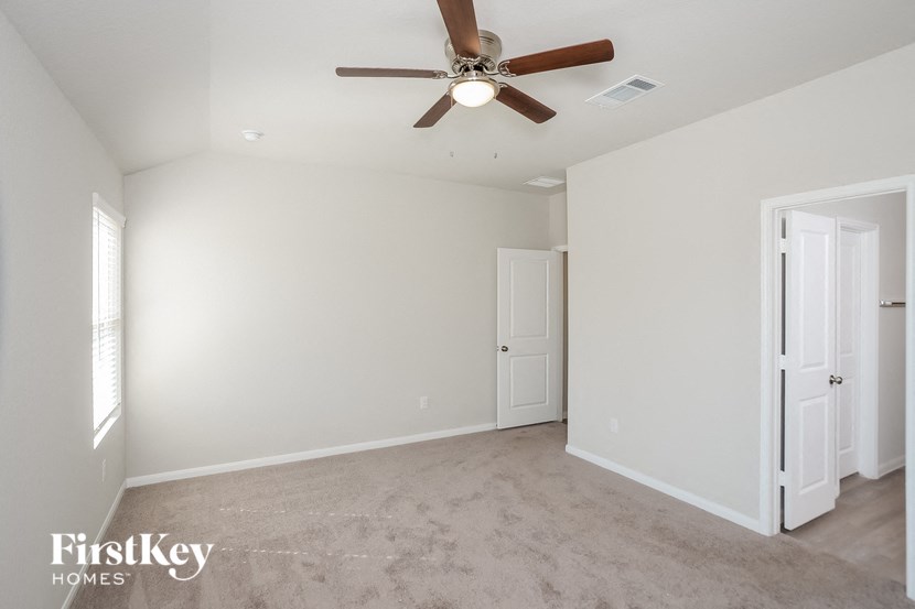 a empty living room with a ceiling fan and white walls