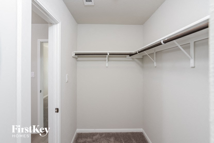 a walk in closet with white walls and a sliding closet door