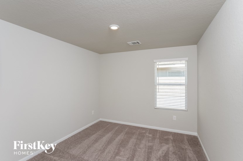 the bedroom of a home with white walls and a window