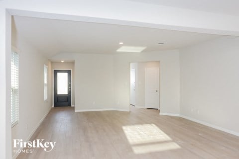 A spacious empty room with wooden floors and white walls.