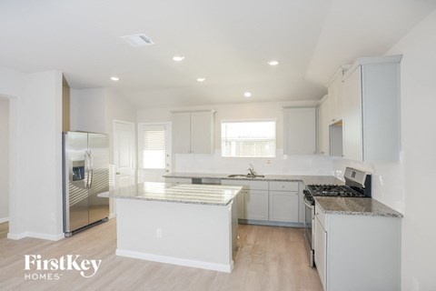 A kitchen with white cabinets and a marble countertop.