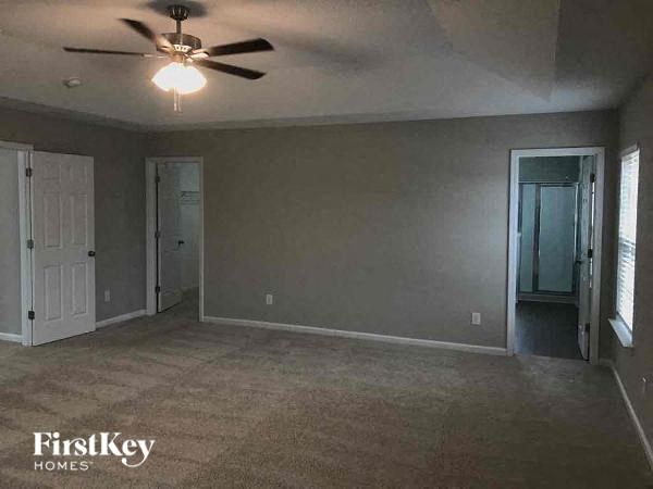 an empty living room with a ceiling fan and a door