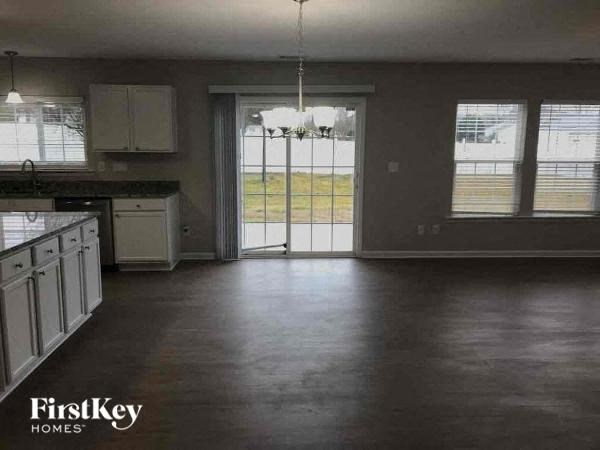 an empty kitchen with white cabinets and a window