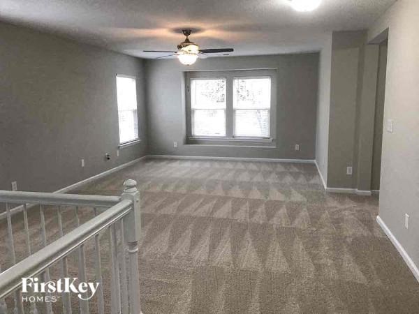 a empty living room with a ceiling fan and a window