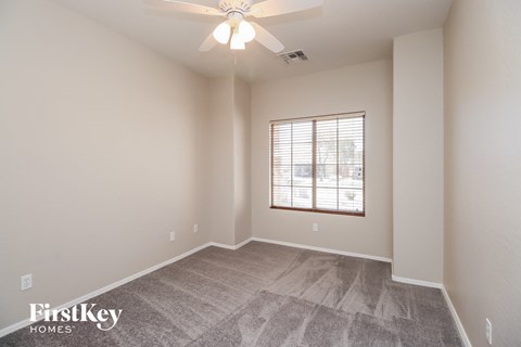 the spacious living room with a ceiling fan and a window