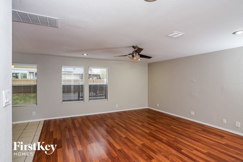 an empty living room with a wood floor and a ceiling fan
