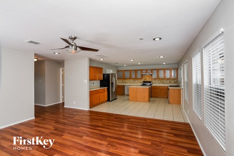 a kitchen and living room with wood floors and a ceiling fan