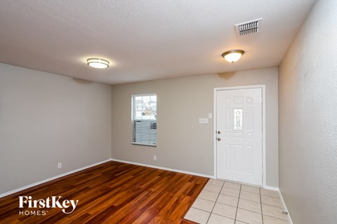 an empty living room with a white door and wood floors