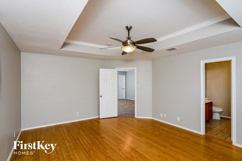 an empty living room with a ceiling fan and a door to a bathroom