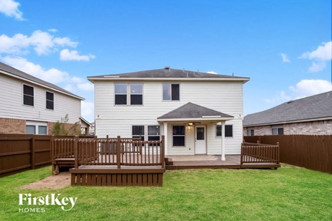 a white house with a wooden deck in a backyard