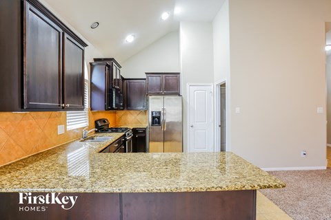 A kitchen with dark wood cabinets and a granite countertop.