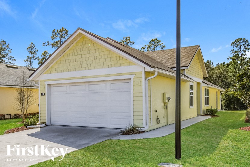 A yellow house with a white garage door is for sale.