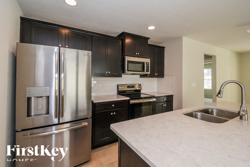 A kitchen with a stainless steel refrigerator and black cabinets.