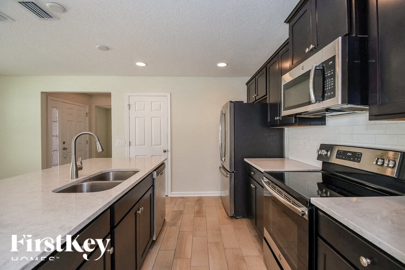 A kitchen with black appliances and wooden floors.