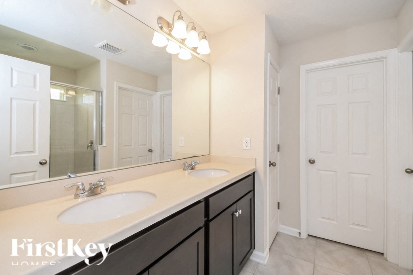 A bathroom with a double sink vanity and a large mirror.