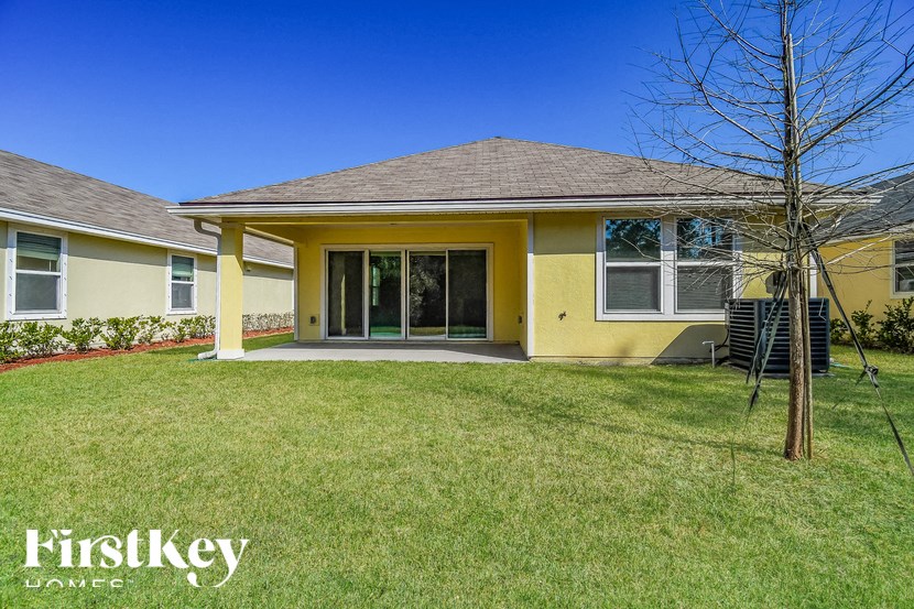 A yellow house with a brown roof and a tree in front.