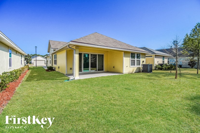 A yellow house with a red brick border in front of it.