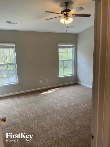 an empty room with a ceiling fan and two windows