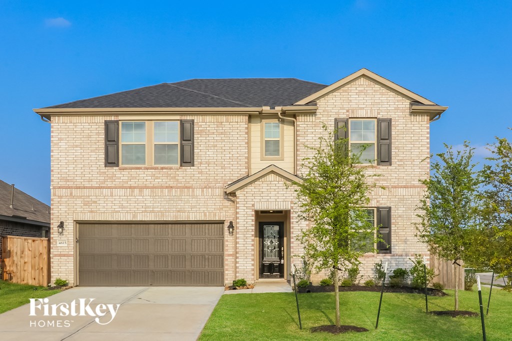 A house with a garage and a tree in front of it.