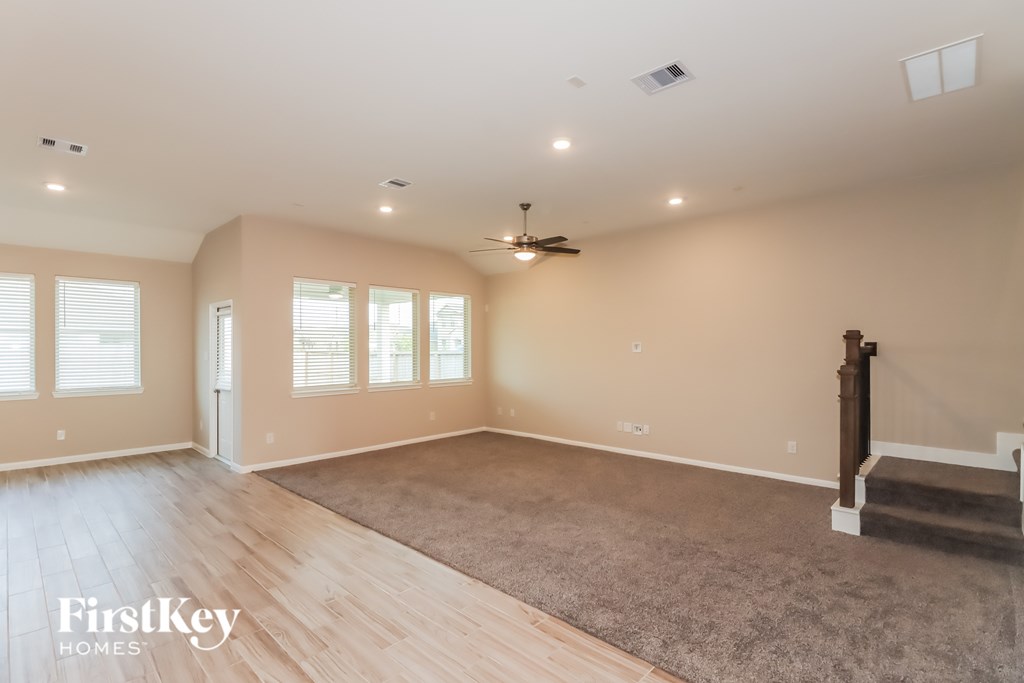 A spacious room with wooden flooring and a rug in the center.