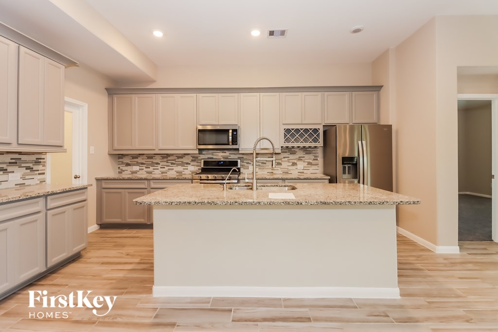 A kitchen with a granite countertop and wooden floors.