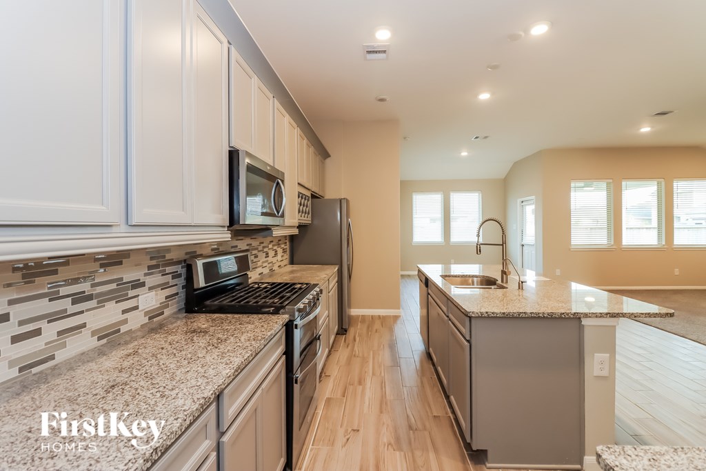 A kitchen with a granite countertop and stainless steel appliances.