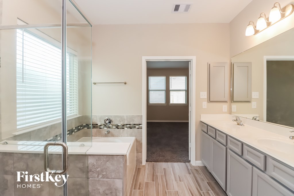A bathroom with a walk-in shower and double sinks.
