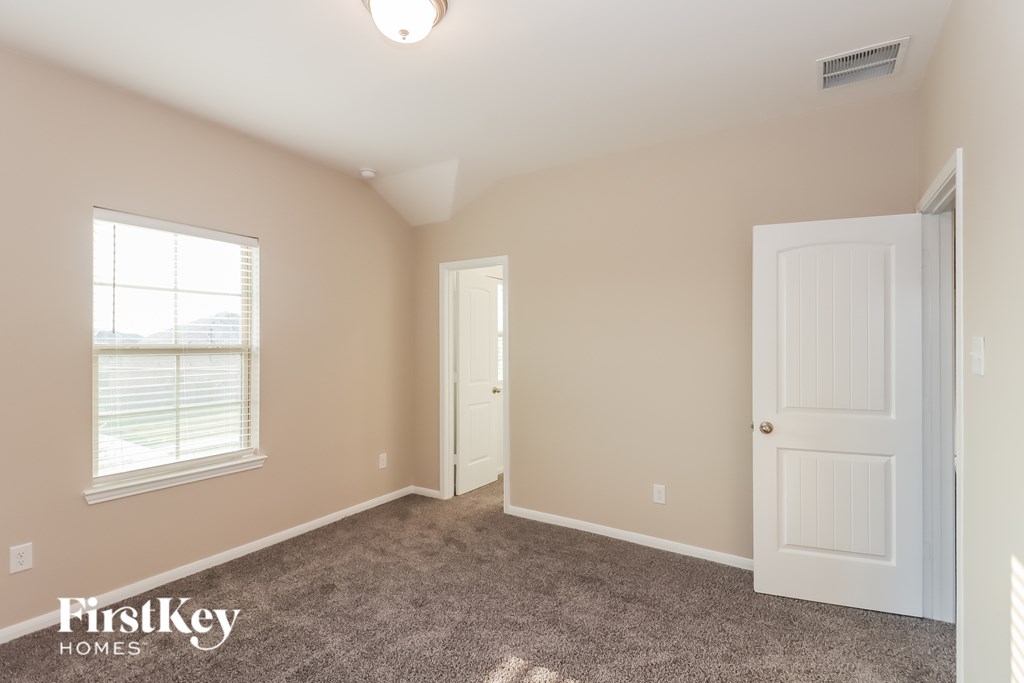 A room with a carpeted floor, two doors, and a window with blinds.