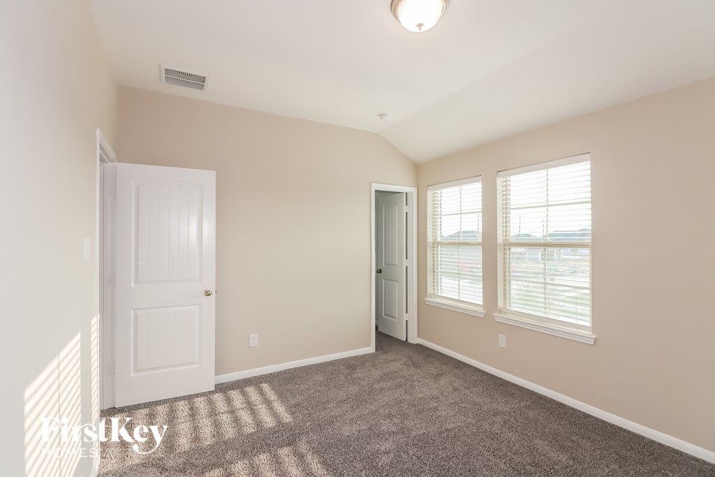 A room with a carpeted floor, two doors, and a window with blinds.