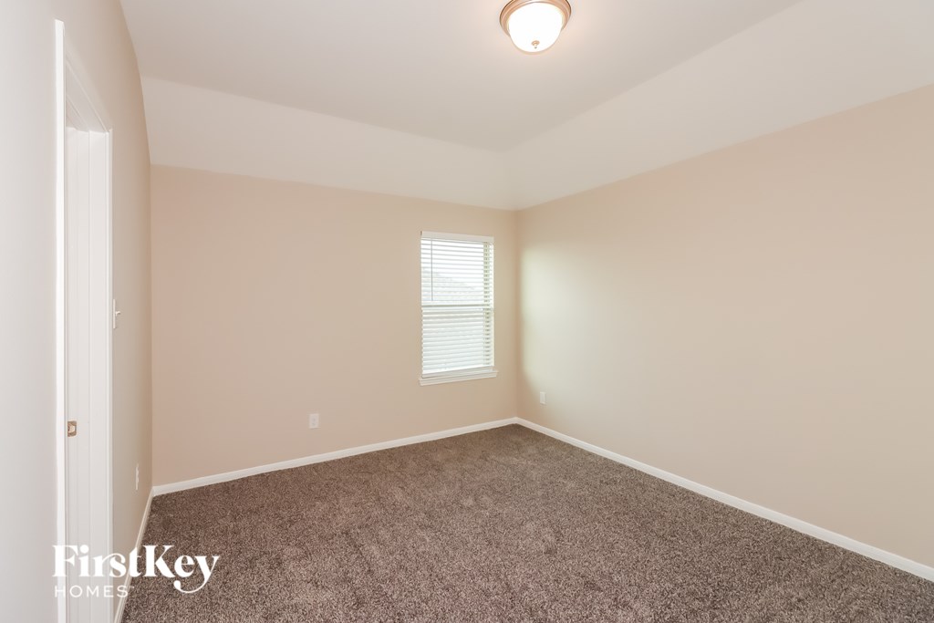 A room with a carpeted floor and a window with blinds.