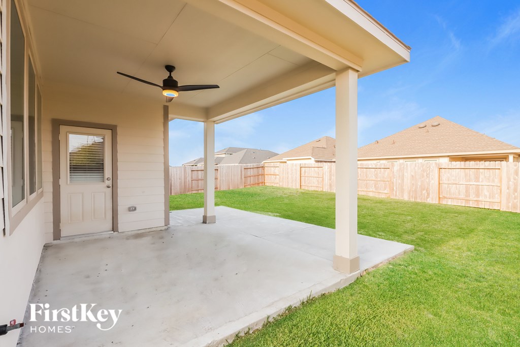 A patio with a ceiling fan and a door leading to a backyard.