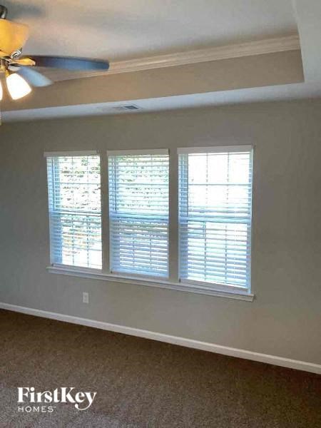 a living room with three windows and a ceiling fan