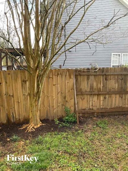 a wooden fence next to a tree in front of a house